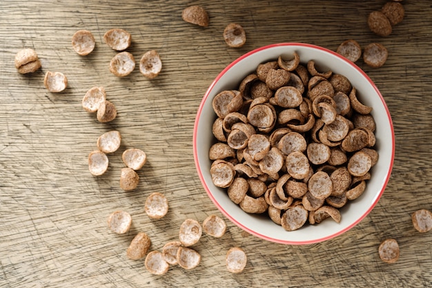 Desayuno de cereales sabor a cacao en un tazón sobre una mesa de madera con espacio de copia, vista superior