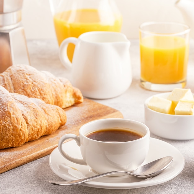 Foto desayuno continental con croissants recién hechos, jugo de naranja y café, enfoque selectivo.