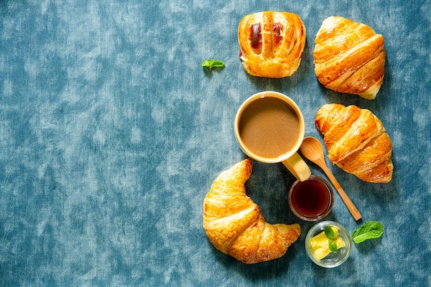 Desayuno continental con croissants recién hechos, jugo de naranja y café, enfoque selectivo.