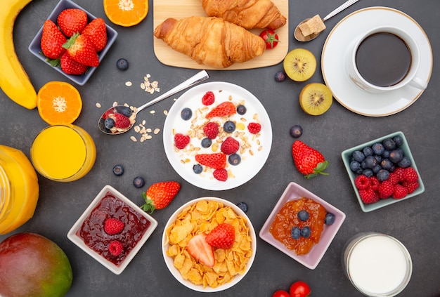 Foto desayuno con copos de maíz mezclados con granos integrales y grupo de frutas.