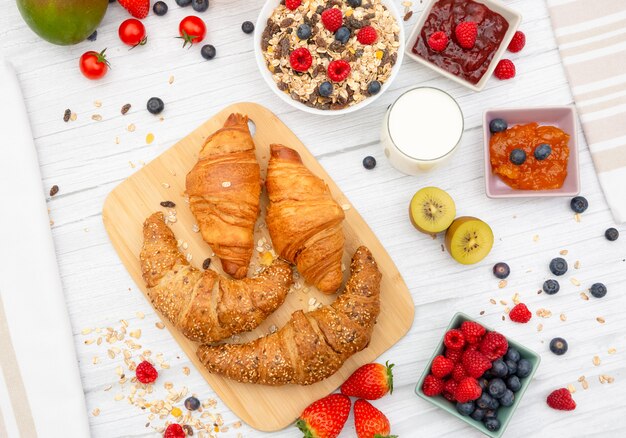 Desayuno con croissant de mantequilla y hojuelas de maíz mezclado con lluvias enteras y grupo de frutas