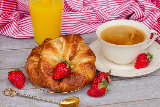 Desayuno con croissants, café, fresas y zumo de naranja natural