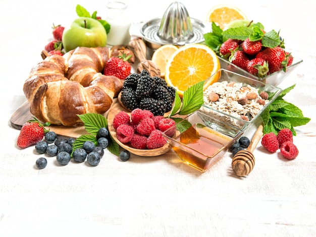 Desayuno con croissants, muesli, frutos del bosque, frutas, leche. Concepto de comida sana