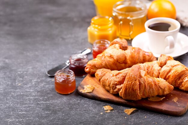 Desayuno con croissants recién hechos y café en la mesa oscura