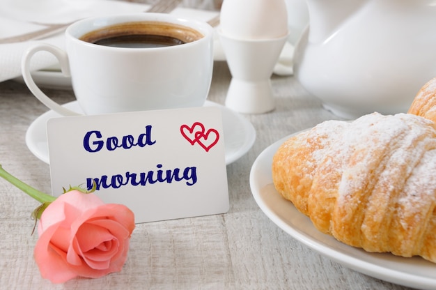 Foto desayuno de croissants relleno de chocolate taza de café de la mañana y una tarjeta con un deseo buenos días