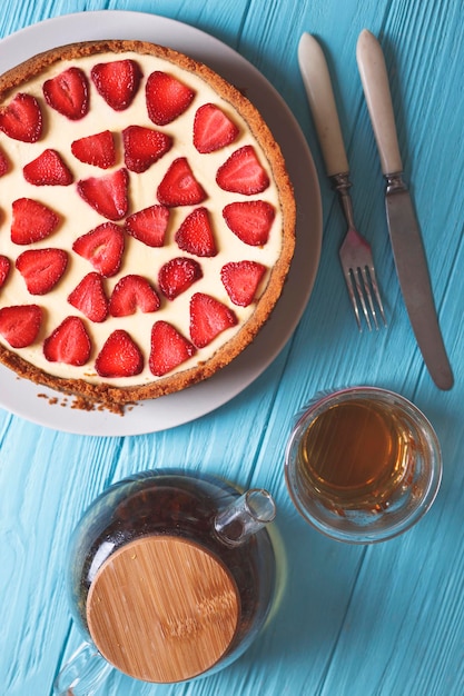 Desayuno delicioso y hermoso. Tarta de queso con fresas sobre un fondo de madera con un ramo de margaritas