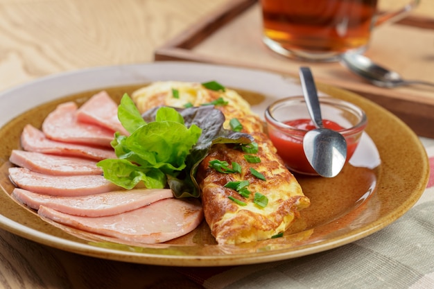 Desayuno delicioso. Tortilla frita con jamón en rodajas de cerca