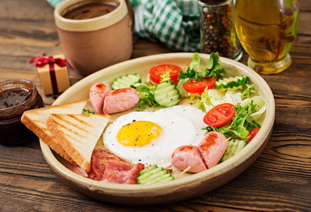 Desayuno en el día de San Valentín - huevo frito en forma de corazón, tostadas, salchicha, tocino