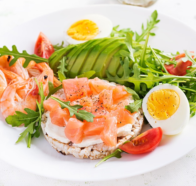 Desayuno de dieta cetogénica. Ensalada de salmón salado con gambas cocidas, gambas, tomate, rúcula, huevos y aguacate. Almuerzo ceto, paleo.