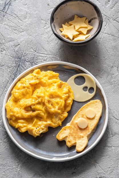 Desayuno divertido para niños con huevos revueltos, queso y cohete espacial de tortilla