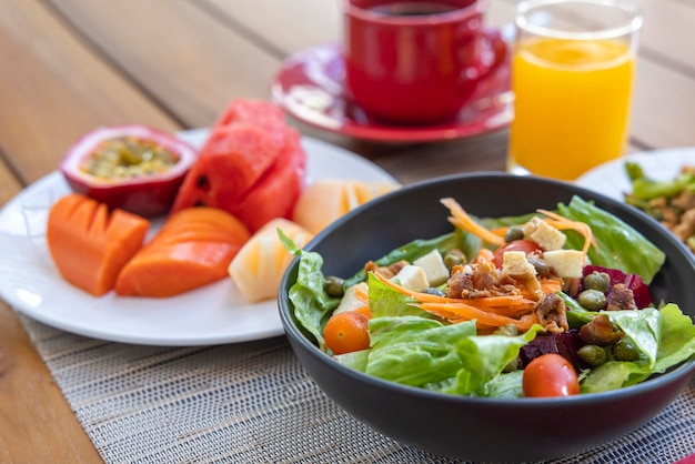 Desayuno Ensalada de verduras frutas como sandía papaya melón maracuyá jugo de naranja y café colocados en un mantel gris