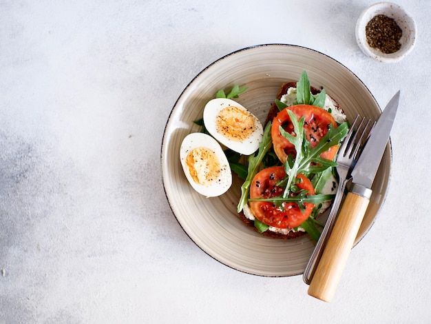 Desayuno equilibrado de sándwich de huevos con tomates de queso verde y café caliente sobre fondo claro Comida dietética