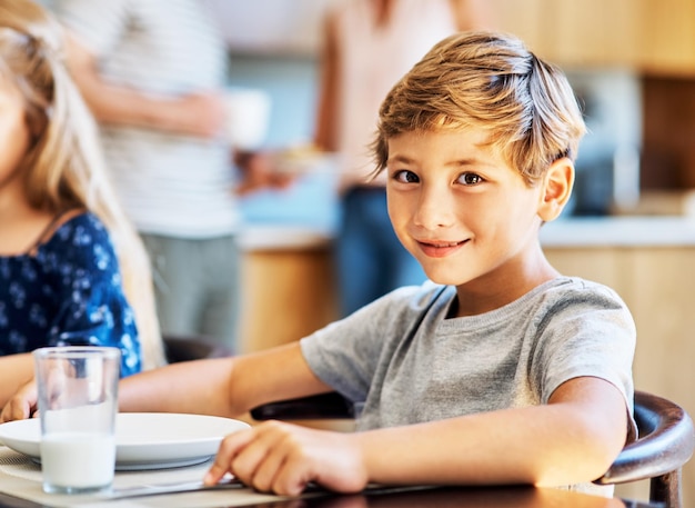 El desayuno es especialmente importante para los niños en crecimiento Retrato de un niño sentado en la mesa del desayuno en casa