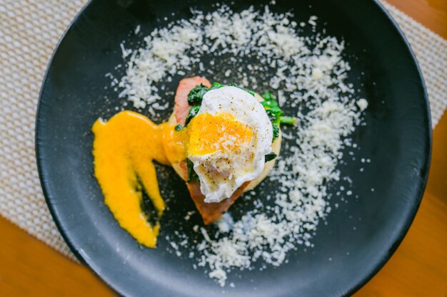 El desayuno es huevo Benedict en plato negro