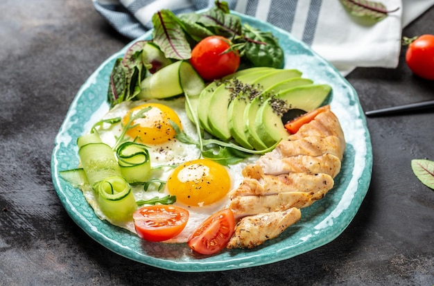 Desayuno con filete de pollo a la parrilla con ensalada tomates frescos pepinos huevos y aguacate Vista superior del menú de la dieta Keto Paleo