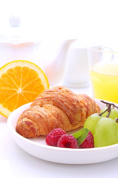 Desayuno de fin de semana: croissants, fruta y zumo de naranja.