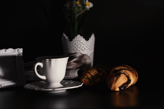 Desayuno francés en la mesa. Croissant de café con chocolate y un decantador con nata. Bollería fresca y café descafeinado.