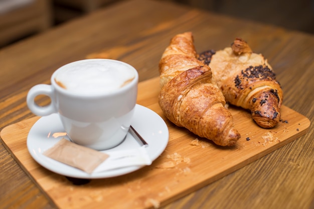 Desayuno francés tradicional con tazas de café caliente y deliciosos croissants frescos colocados en una mesa vintage