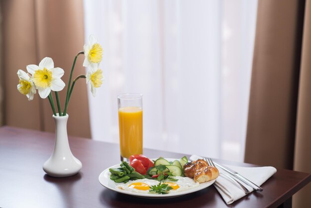 Desayuno fresco con huevos revueltos y jugo de naranja en la habitación del hotel