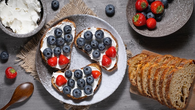 Desayuno fresco con sándwiches de arándanos, fresas y ricotta centeno