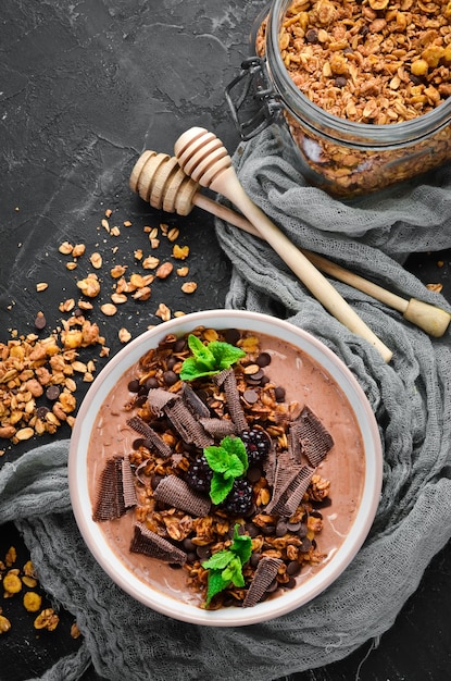 Desayuno fresco con yogur, granola, chocolate y bayas en un bol. Vista superior. Espacio libre para su texto.