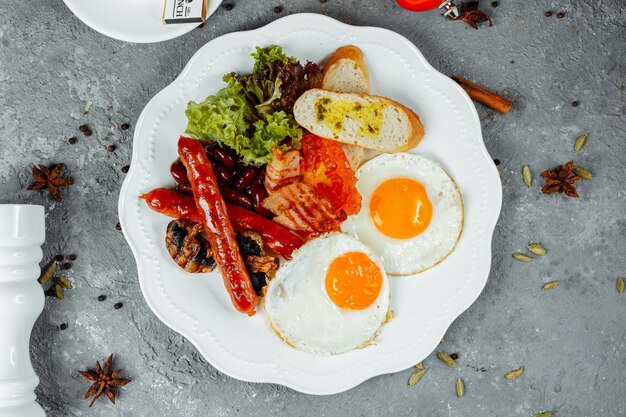 Desayuno frito con tocino, salchichas y frijoles horneados.