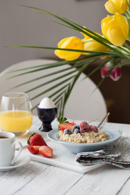 Desayuno gachas de avena con frutas bayas y taza de café.