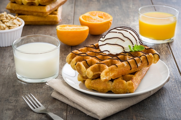 Desayuno de gofres con jugo de helado, frutas y cereales en la mesa de madera