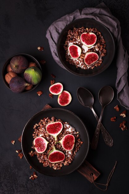 Desayuno con granola e higos. Platos negros con un desayuno fresco y saludable. Comida sana