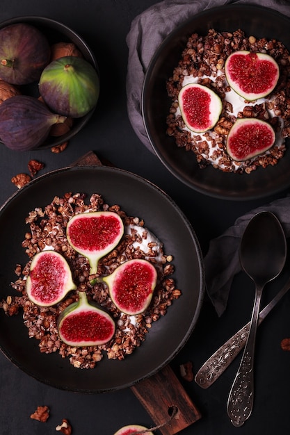 Desayuno con granola e higos. Platos negros con un desayuno fresco y saludable. Comida sana