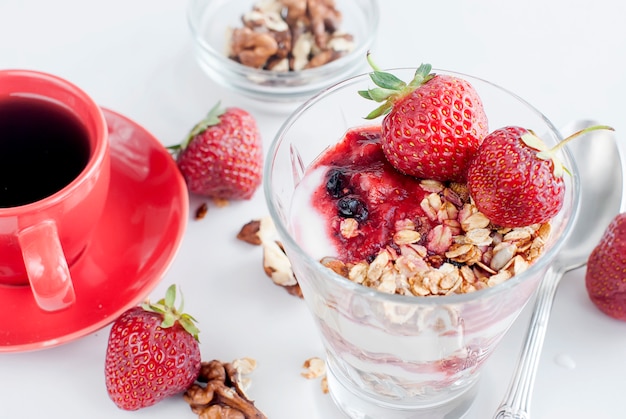 Desayuno granola, fresa y una taza de café.