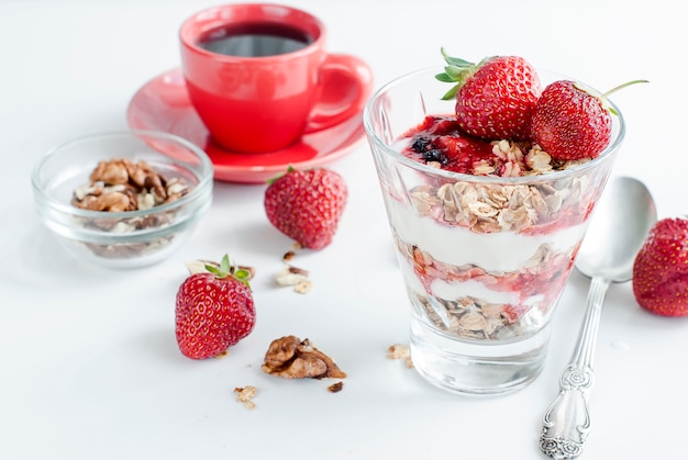 Desayuno granola, fresa y una taza de café.