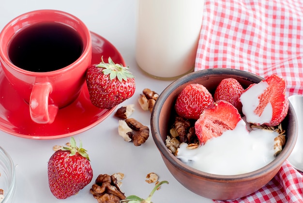 Desayuno granola, fresa y una taza de café.