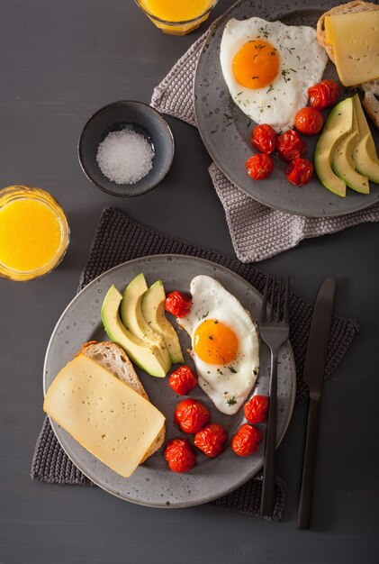 desayuno con huevo frito cerca de aguacate y tomate con queso