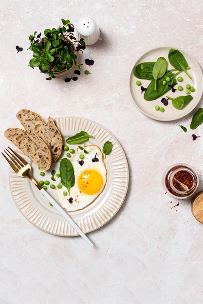 Desayuno de huevo saludable con espinacas y microgreens, vista superior en mesa de mármol