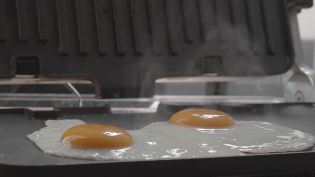 Desayuno con huevos fritos cocidos en parrilla eléctrica