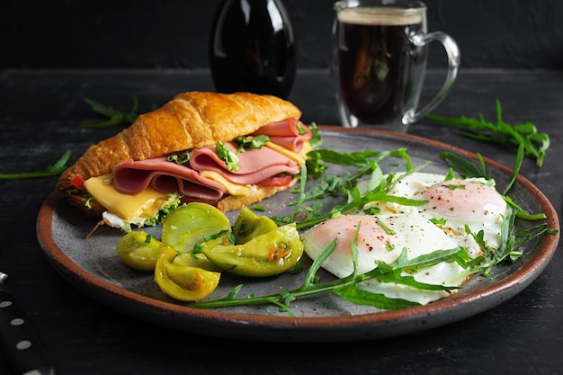 Desayuno con huevos fritos y croissant sandwith con jamón queso y ensalada Delicioso desayuno matutino