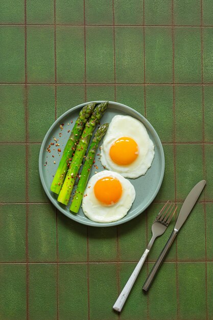 Foto desayuno huevos fritos con espárragos frescos y jamón de jamón en un plato