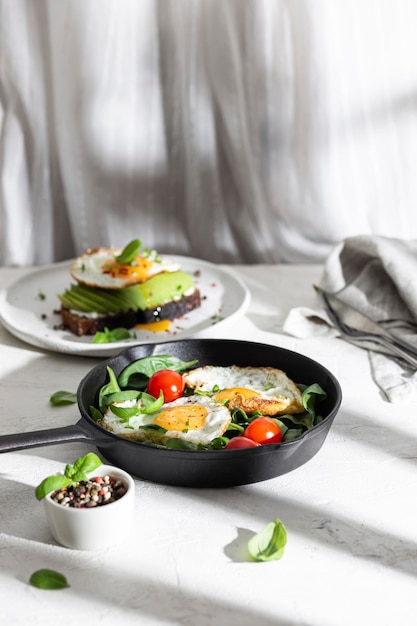 Desayuno con huevos fritos y verduras en una sartén.