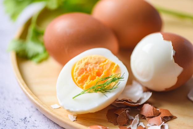 Desayuno de huevos, menú de huevos frescos pelados, huevos cocidos en un plato de madera decorado con hojas de eneldo verde y cáscara de huevo, yemas de huevo cortadas a la mitad para cocinar una alimentación saludable