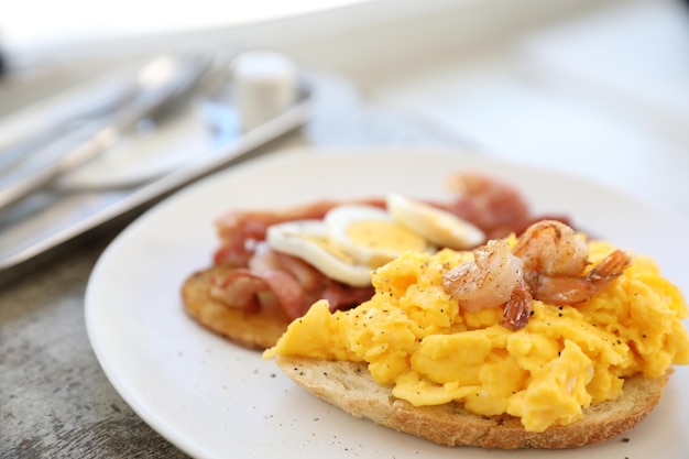 Desayuno con huevos revueltos, papas fritas, tocino y camarones