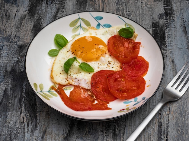 Desayuno con huevos revueltos y tomates frescos en un plato coloreado