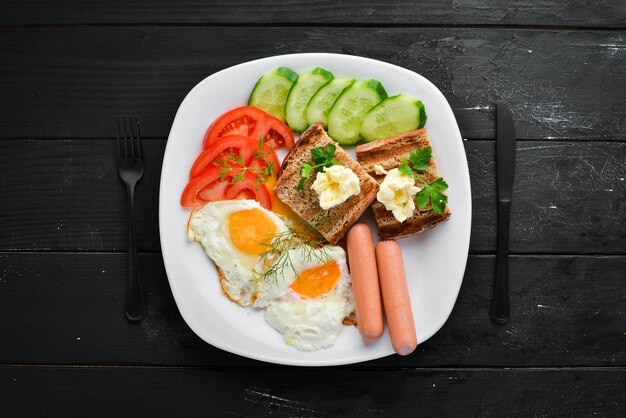 Desayuno huevos salchichas y verduras en el plato Vista superior Espacio libre para su texto Estilo rústico