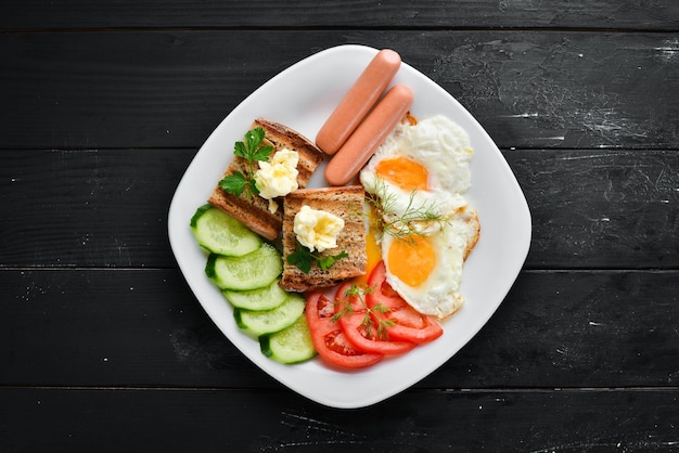 Desayuno: huevos, salchichas y verduras en el plato. Vista superior. Espacio libre para su texto. Estilo rústico.