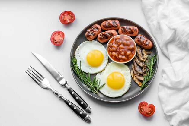 Desayuno inglés completo frijoles huevos fritos salchichas asadas tomates champiñones en una mesa de hormigón oscuro con pan tostado