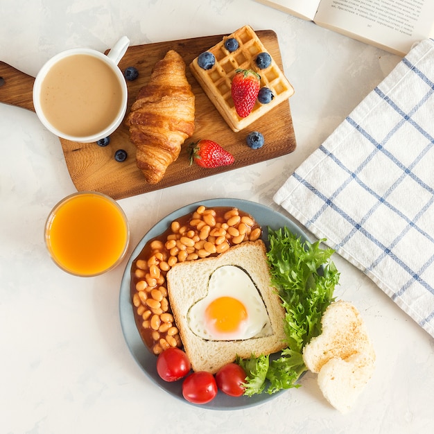 Desayuno inglés completo con huevos fritos, frijoles, tostadas, ensalada, tomates en blanco