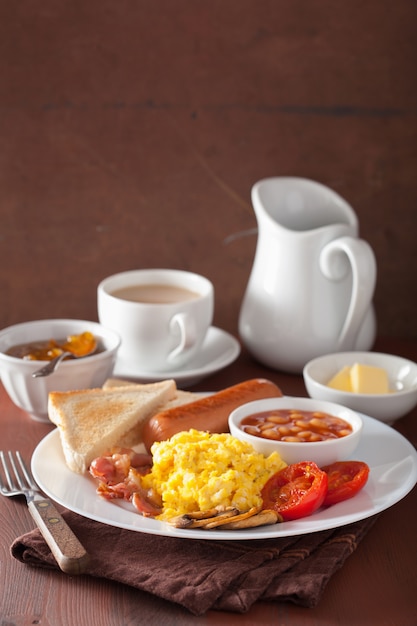 Desayuno inglés completo con huevos revueltos, tocino, salchichas, frijoles, tomate.