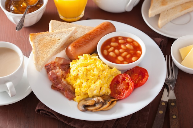 Foto desayuno inglés completo con huevos revueltos, tocino, salchichas, frijoles y tomate.