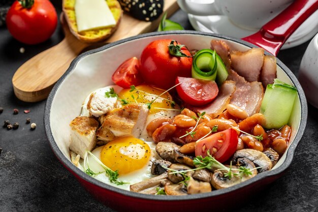 Desayuno inglés completo tradicional con huevos fritos frijoles champiñones a la parrilla y tocino sobre fondo negro Fondo de recetas de comida Cerrar