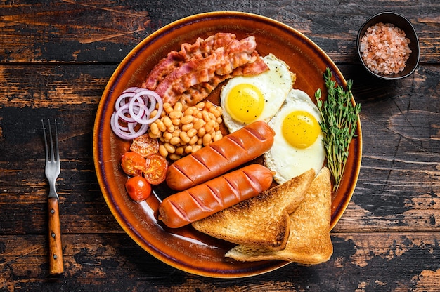 Desayuno inglés completo tradicional con huevos fritos, salchichas, tocino, frijoles y tostadas.